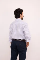 Camisa de manga larga con estampado a cuadros en tonos azul, gris y blanco. Tiene cuello abotonado, bolsillo en el pecho y corte clásico.