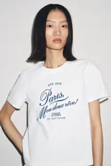 Camiseta blanca de algodón con cuello redondo y mangas cortas. Estampado frontal con la frase "Paris, Mon doux rêve!" en azul marino.