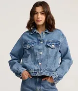 Campera boxy de jeans azul, con cuello clásico, cierre frontal con botones, bolsillos con solapas abotonadas en el pecho y recortes.