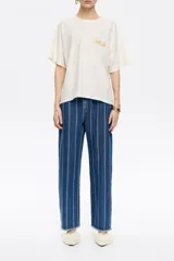 Pantalón denim azul con rayas verticales blancas, corte recto, largo tobillero y bajo desflecado.