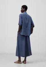 Camisa azul de lyocell, de corte holgado, con cuello mao, manga corta japonesa y botonadura frontal oculta.