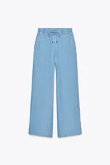 Pantalón celeste de tiro alto con cintura elástica ajustable con cordones, bolsillos delanteros y traseros, y pernera ancha.