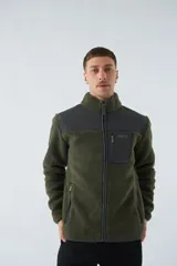 Campera de sherpa verde con detalles en negro, cuello alto, cierre frontal y bolsillo con cierre en el pecho.