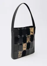 Bolso tipo tote de cuero negro con diseño patchwork que combina cuero liso, charol y estampado animal print. Tiene asa de hombro y cierre con mosquetón.