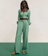 Pantalón wide leg color verde agua, de tiro alto y corte sastrero, con cintura elástica en la espalda, cinturón incorporado para lazo, pliegues delanteros y bolsillos laterales.