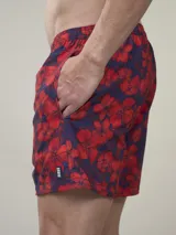 Short de baño verde con estampado de margaritas blancas y cordón ajustable naranja.