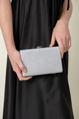 Cartera de mano rectangular plateada con lurex y cierre metálico plateado.