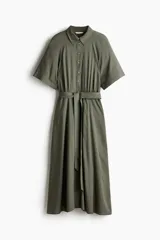 Vestido midi color verde oliva con cuello camisero, botonadura frontal y mangas raglán cortas. Tiene elástico fino en la parte posterior de la cintura, frunces adelante y atrás, y cinturón extraíble para atar.