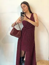 Vestido midi de encaje color borgoña con estampado de flores. Tiene escote en V, corte asimétrico y detalle drapeado en la cintura.