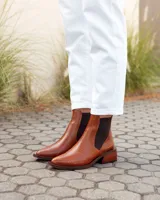 Botas estilo Chelsea de cuero vacuno color marrón con textura grabada tipo reptil. Presentan paneles elásticos laterales en color negro, puntera almendrada y taco cuadrado de madera.