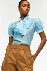Blusa color amarillo pálido de lyocell, con mangas abullonadas con terminaciones elásticas y lazo XL en el cuello.