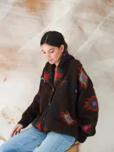 Saco de lana marrón con diseño geométrico multicolor, cuello con solapa, cierre frontal con botones y bolsillos delanteros.