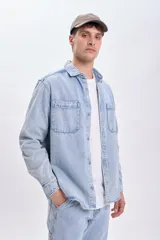 Sobrecamisa de jean celeste con dos bolsillos frontales con solapa y cierre abotonado.
