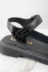 Sandalias negras de cuero con plataforma y tiras ajustables.