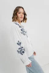 Camisa de manga larga en algodón liviano, color azul marino, con bordados florales en contraste en el frente y mangas. Cuello mao con terminación en ondas y puños fruncidos.