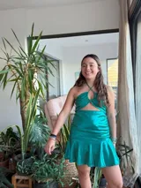 Vestido corto con estampado de rayas horizontales en tonos grises y negros. Diseño con escote halter que se ata al cuello, abertura central en el busto y falda corta con volado.