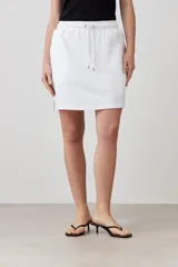 Minifalda blanca de corte recto, con pretina elastizada con cordón ajustable y bolsillos laterales.