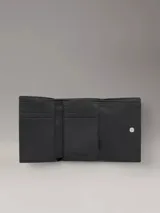 Billetera triple Calvin Klein de cuero sintético texturizado color negro, con logo metálico plateado. Incluye seis ranuras para tarjetas, dos ranuras para billetes y un compartimento para monedas con cremallera.