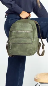 Mochila color rosa de símil cuero con bolsillos frontales con cierre. Tiene asa de mano rígida y correas regulables.