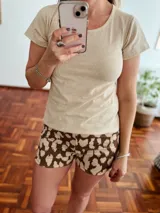 Conjunto de pijama de dos piezas, compuesto por una remera de manga corta color beige y un short con estampado de manchas marrones.