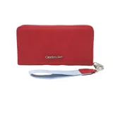 Billetera marrón con diseño acolchado en forma de V y logo metálico con forma de labios. Incluye cierre perimetral y correa de mano desmontable roja.
