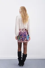Falda corta tipo mini de lentejuelas multicolor, con degradado de tonos rosados, morados, azules y toques de amarillo y naranja.