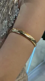 Brazalete rígido dorado con textura martillada.