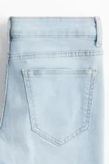 Pantalón de jean celeste de tiro bajo, corte ajustado en la cadera y acampanado desde la rodilla.