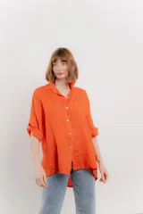 Camisa de lino color coral, de corte amplio, con cuello camisero, botones frontales y mangas 3/4 arremangables.
