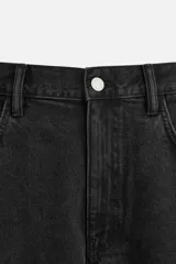 Bermuda de jean color negro, corte amplio, con cinco bolsillos, efecto lavado y cierre frontal con cremallera y botón.