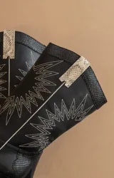 Bota de caña media color negro con puntera levemente puntiaguda, taco cuadrado y diseño bordado en hilo blanco.