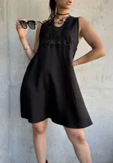 Vestido corto negro con escote en V, breteles finos y detalle de encaje en el busto.