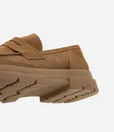 Mocasín masculino de gamuza color marrón con suela track dentada y puntera redonda. Posee el detalle clásico de antifaz sobre el empeine y costuras visibles al tono.