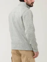 Buzo polar color gris jaspeado con cuello alto, medio cierre frontal y bolsillos laterales. Confeccionado con fibras de poliéster reciclado.