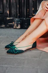 Bailarinas con aberturas laterales, de raso flocado verde botella. Cuentan con cordones del mismo tono para atar y plantilla de lana.