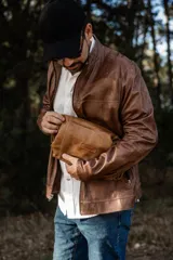 Necessaire de cuero natural marrón confeccionado artesanalmente, con diseño funcional y atemporal. Presenta laterales ajustables, cierre superior metálico y un parche frontal con el logo de la marca Soriame. Interior forrado y reforzado para mayor durabilidad.