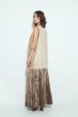 Chaleco largo color beige claro, estilo chaleco de gamuza, con apliques metálicos circulares perforados y largos flecos en el ruedo.