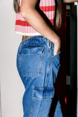 Pantalón cargo de jean celeste con lavado esfumado, tiro bajo, pierna ancha y bolsillos cargo.