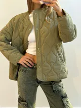 Campera verde militar con diseño capitoneado, cuello redondo y cierre frontal con botones a presión.