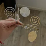 Brazalete rígido dorado y plateado con apliques de espirales y círculos calados.