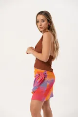 Minifalda multicolor con estampado abstracto en tonos rosa, naranja y violeta, con nudo lateral.