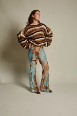 Pantalón de tiro medio con elástico en la cintura y corte acampanado. Diseño con estampado abstracto en tonos marrones, rojizos y amarillos, con textura tipo piel de reptil.