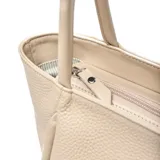 Cartera grande tipo tote bag de cuero color beige claro, con textura granulada. Presenta dos asas de hombro fijas y un diseño con pliegues verticales a los lados. Tiene cierre principal y bolsillo interno con cierre.