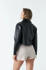 Sobrecamisa cropped de cuero sintético color negro, con cuello clásico, cierre frontal con botones, mangas largas y bolsillos frontales con solapa.