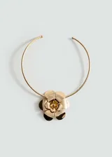 Gargantilla rígida dorada con aplique de flor metálica.