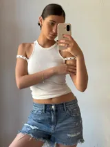 Musculosa blanca con cuello redondo y breteles anchos con ojales metálicos.