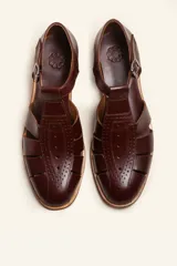 Sandalias de cuero color marrón claro, con diseño de tiras entrecruzadas y hebilla lateral.