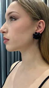 Aros negros con forma de flor con pétalos texturizados.