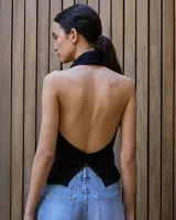 Top tejido de punto color negro, con escote halter pronunciado y espalda descubierta.