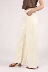 Pantalón de jean color crudo, de corte palazzo y tiro alto, con bolsillos delanteros y traseros, y costuras a la vista.